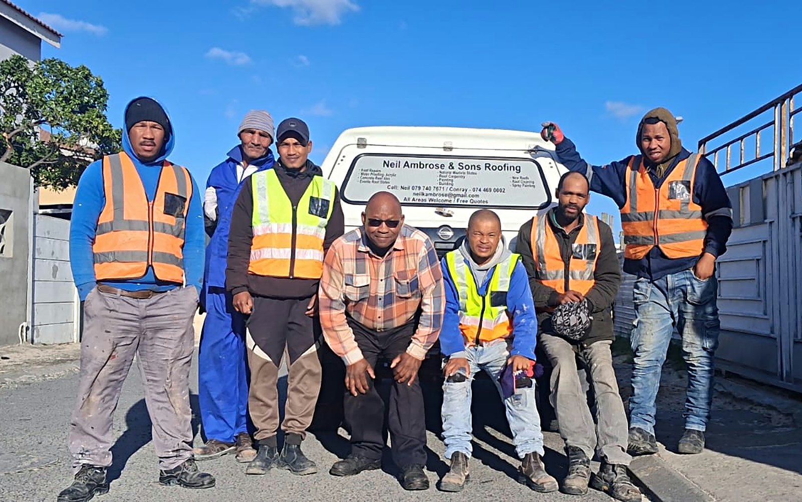 Neil Ambrose and his roofing team in high-visibility vests in front of the company bakkie
