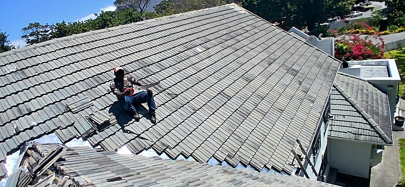 Roofer replacing tiles on a large pitched roof